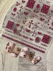 Macro view of 3D nail stickers featuring pink leopard print, crosses, and alphabet details