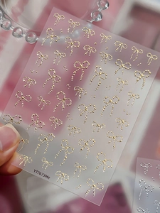 Macro view of 3D embossed bow nail art stickers in gold and silver pearl textures