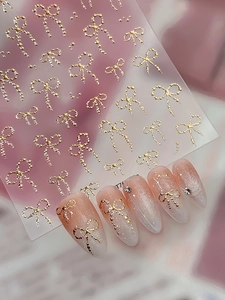 3D embossed golden bow nail art stickers with metallic texture on pink glitter nails