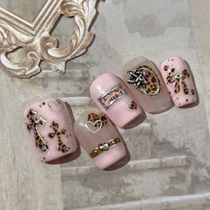 Pink leopard print press-on nails with silver metal cross and heart charms