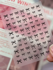 Détail d'autocollants pour ongles avec nœuds noirs en relief de différentes tailles