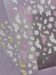Macro shot of 5D embossed nail stickers featuring floral and butterfly 3D textures