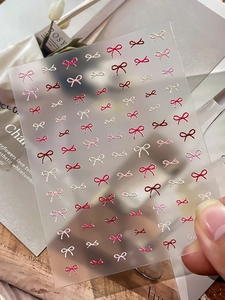 Macro shot of 3D embossed red bow nail art stickers with delicate glossy textures