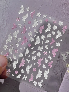 Detail of 3D embossed nail stickers featuring white and pink flower and butterfly patterns