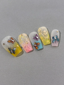 Detail of long ballerina press-on nails with glitter butterflies and 3D floral designs