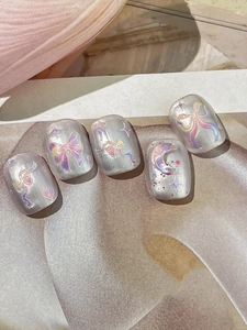 Detail of silver cat-eye press-on nails with laser bow and moon patterns