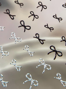 Macro detail of 3D bow-knot nail art stickers with black and white polka dot patterns