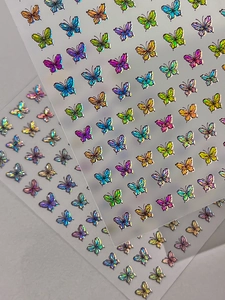 Close-up of holographic butterfly nail art stickers with iridescent rainbow laser effect