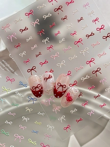 Detailed view of 3D embossed bow nail stickers with red French tips and polka dot designs
