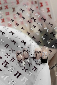 Close-up of 3D embossed nail stickers featuring black and white bows and polka dots