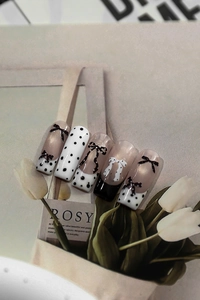 Detail of black and white polka dot nail stickers with 3D bows and French style design
