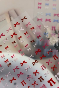 Detailed view of colorful bow-shaped nail stickers with polka dots on a translucent sheet