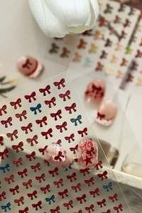 Macro view of 5D embossed red bow nail stickers with gold glitter and 3D floral details