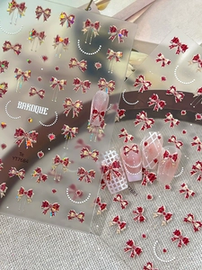 Detailed close-up of baroque style red bow and heart embossed nail art stickers