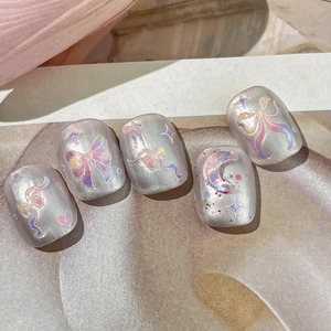 Pearlescent silver press-on nails with rainbow bows, stars, and moon dreamlike patterns