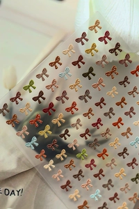 Detailed view of 3D embossed bow nail stickers with polka dots on a neutral fabric background