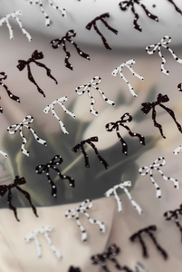Macro detail of bow-shaped nail stickers with black and white polka dots on clear film