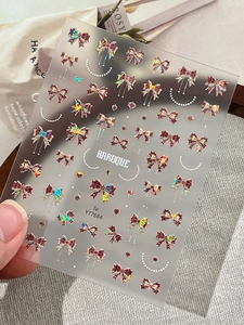 Detail of 3D embossed red holographic bow nail stickers with elegant Baroque typography