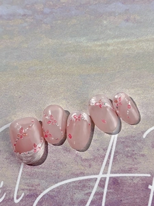 Vue macro de faux ongles faits main rose dégradé avec motifs papillons et perles argentées