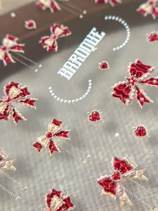 Macro detail of Baroque 3D nail art stickers with red bows, pearls, and golden accents