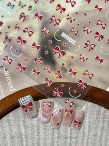 Detail of 3D embossed nail stickers featuring red bow knots and baroque gold hearts
