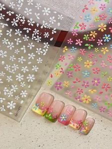 Vue macro de stickers d'ongles 3D en relief avec marguerites blanches sur faux ongles