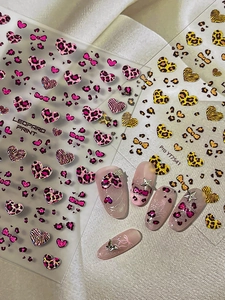 Detail of leopard print nail stickers with pink hearts and stars on long nail tips