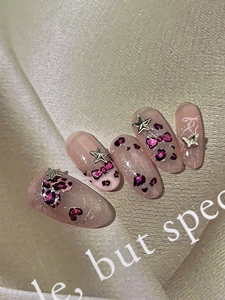 Detail of pink leopard print press-on nails with 3D stars and butterfly charms