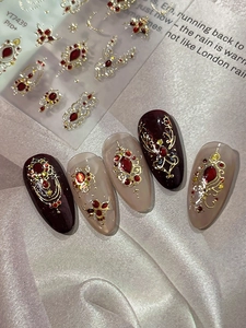 Macro view of 3D embossed baroque nail stickers with gold lines and red gemstones