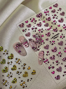Detailed close-up of leopard heart nail stickers with pink and yellow patterned nail art set