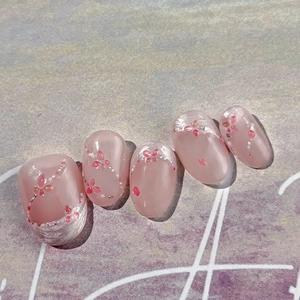 Faux ongles rose gelée avec motifs floraux blancs et touches de paillettes argentées