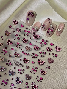 Detailed view of leopard heart nail stickers and 3D butterfly charms on soft pink nails