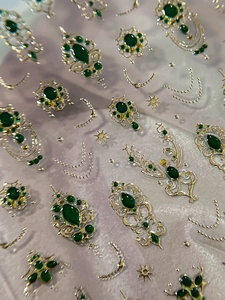 Macro detail of 3D baroque nail stickers with emerald gems and golden embossed relief
