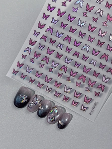 Macro shot of purple laser butterfly nail stickers with metallic edges on gradient nails