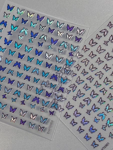 Detailed holographic butterfly nail art stickers in shifting blue and purple metallic tones