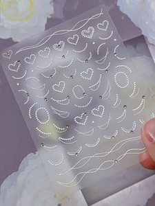 Detailed view of 3D embossed heart nail stickers with delicate rhinestones and white bead patterns