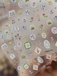 Macro detail of embossed floral nail art stickers featuring colorful tulips and lavender