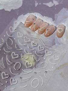Close-up of embossed heart nail stickers with elegant 3D pearls and rhinestone designs
