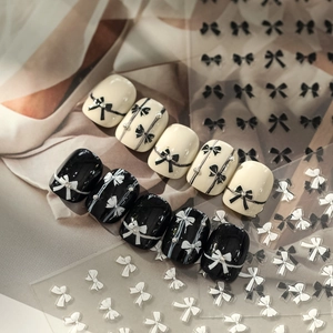 Chic black and white bow nail art stickers with metallic rivets on nail polish tips