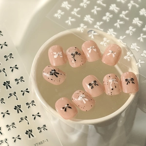 Cute black and white bow nail stickers with nude pink press-on nails and silver beads