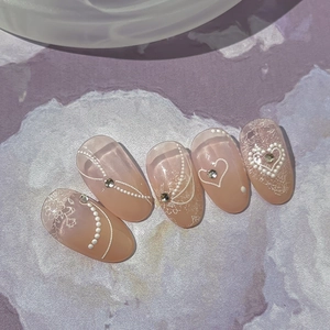 Pink gradient press-on nails with white lace, pearls, and 3D heart charms in a set