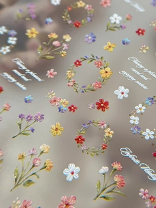 Macro shot of 3D embossed floral nail stickers featuring colorful flowers and lettering