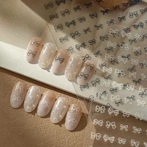 Close-up of black and white bow nail art stickers with decorative manicured nails