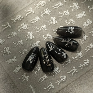 Macro shot of YT486 bow nail stickers and dark style press-on nails with silver crosses