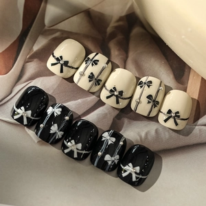 Detailed close-up of bow-patterned black and white adhesive nail art stickers and decals
