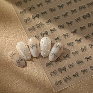 Minimalist black bow nail stickers on pink gradient nails with pearl decorations