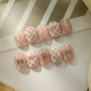 Pink cat-eye press-on nails with silver metal bow and black-white line pattern