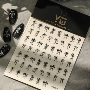 Close-up of black 3D bow-knot nail art stickers on YT486 packaging over gray surface