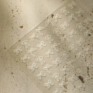 Detailed view of white minimalist bow nail art stickers with embossed texture details