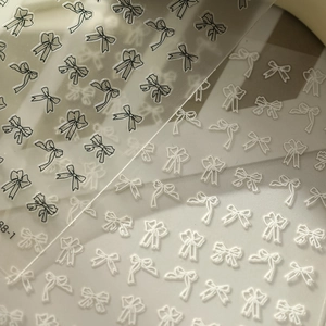 Detail of adhesive bow nail stickers with black and white line patterns for manicure